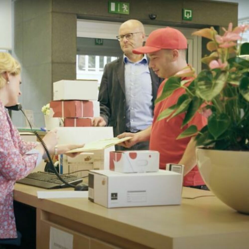Receptionist handing a parcel to a courier at the front desk
